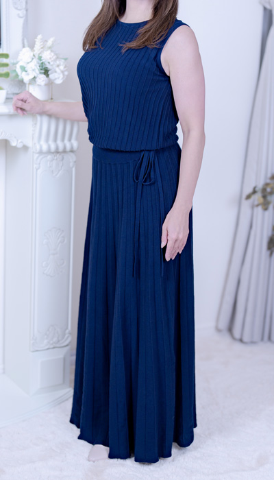 ネイビーのロングワンピースを纏った、落ち着いた大人の知性を感じさせる佇まいの熟女の女性。